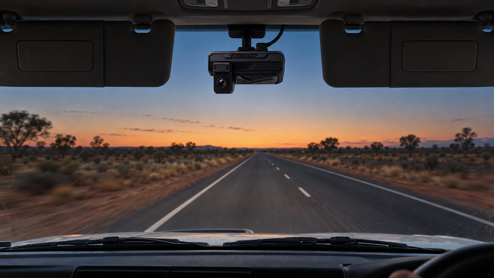 Editorial image: a vehicle interior at dusk, camera visible on the screen line. No text in the artwork.