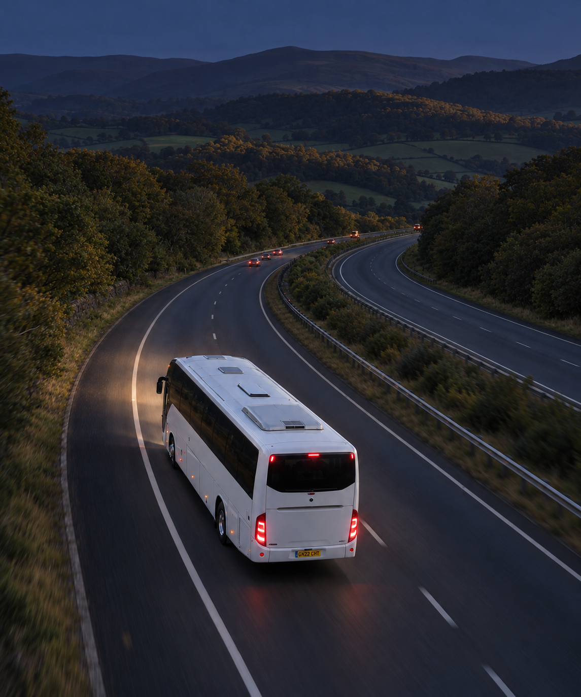 Photograph: a coach on a highway at dusk, shot from height. Dark and cool, room at the top, no text in the artwork.