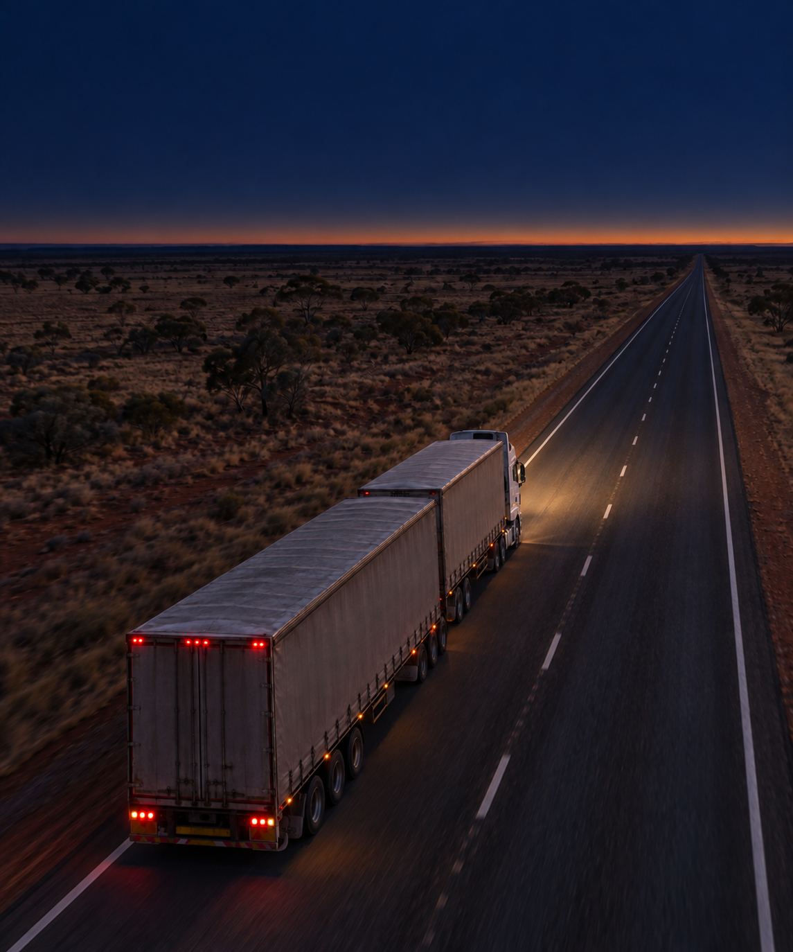 Photograph: a line-haul semi on an open highway at dusk, shot from height. Dark and cool, room at the top, no text in the artwork.