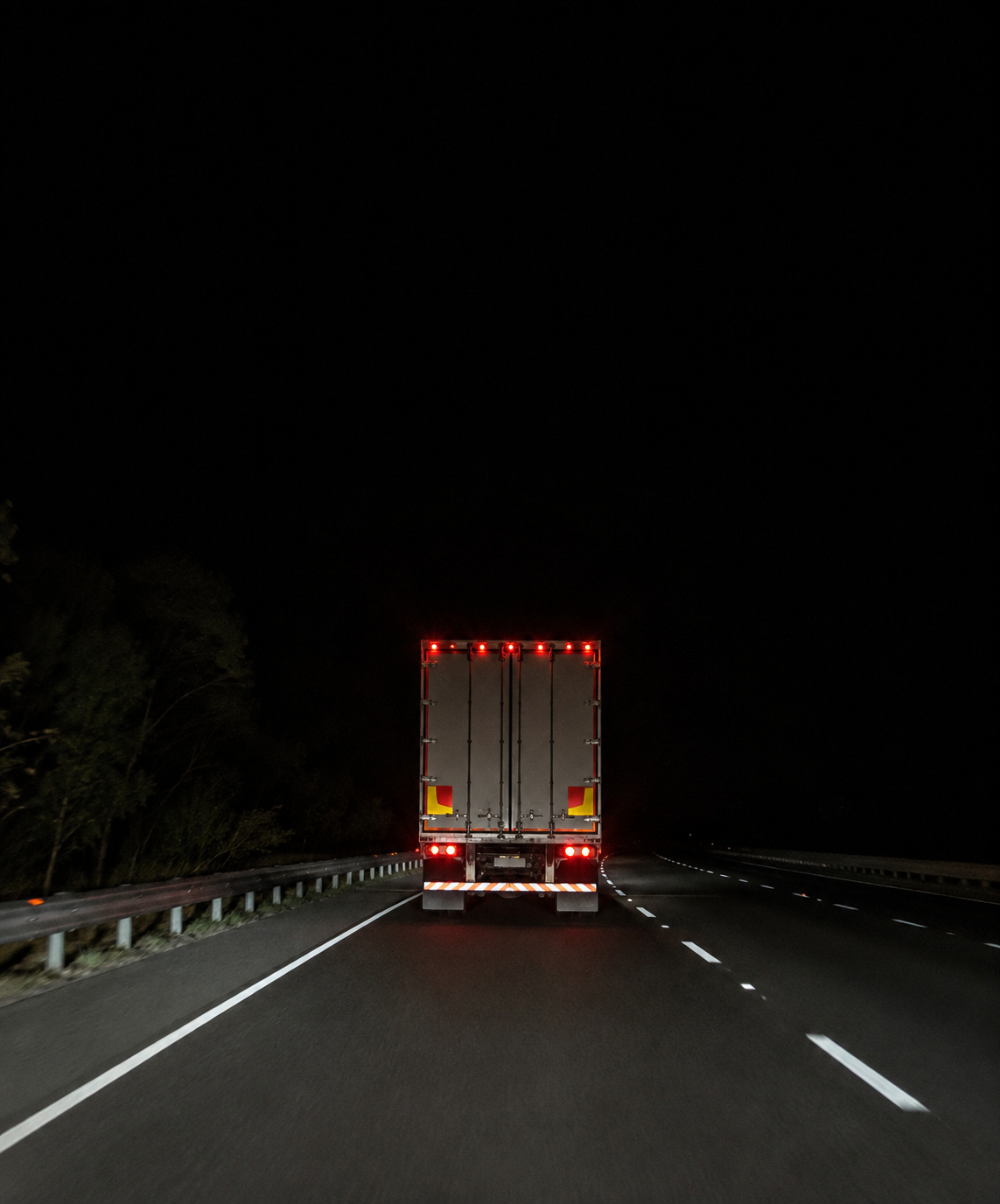 Photograph: a night highway shot from a following vehicle. Dark and cool, room at the top, no text in the artwork.