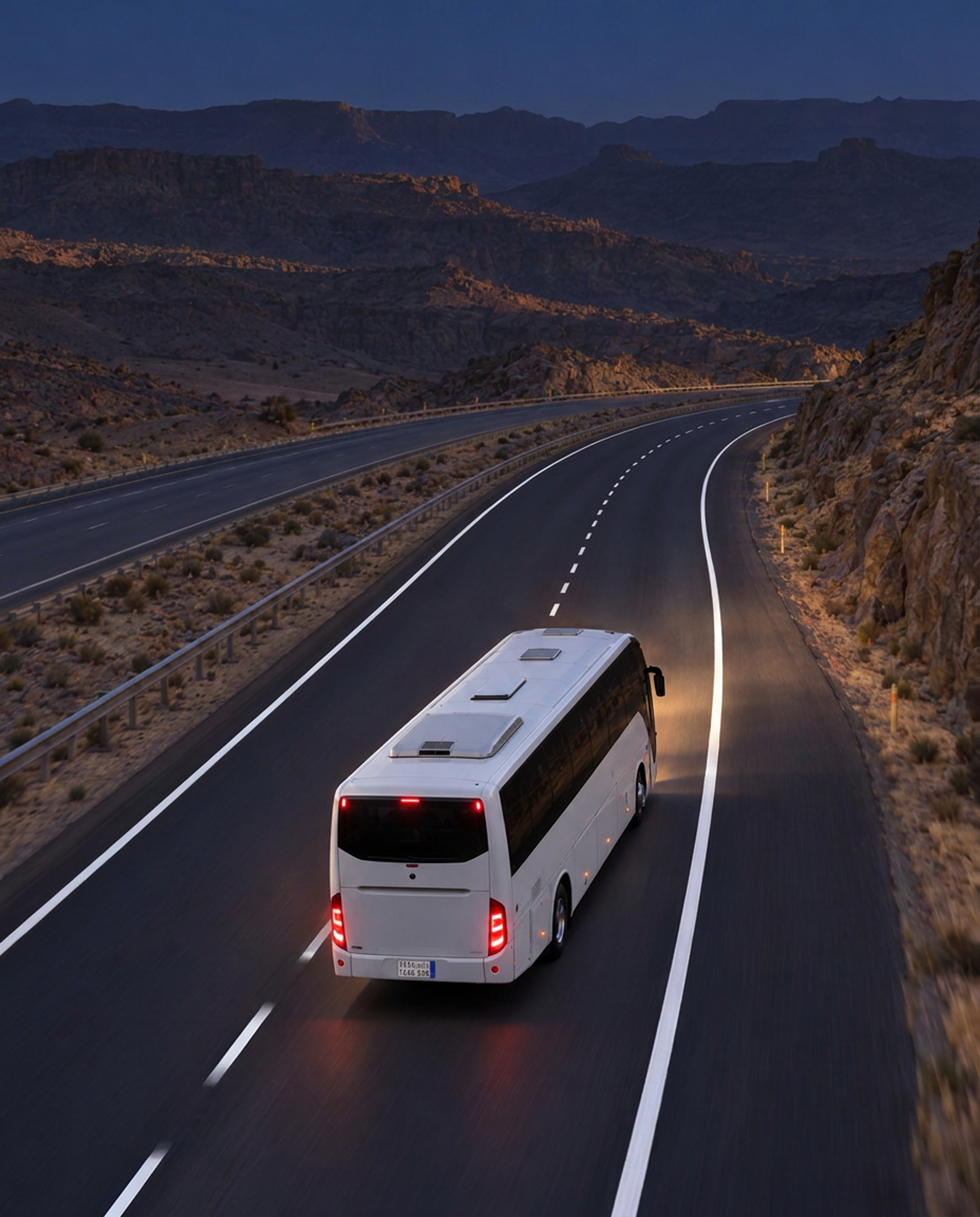 Photograph: a coach on a highway at dusk, shot from height. Dark and cool, room at the top, no text in the artwork.