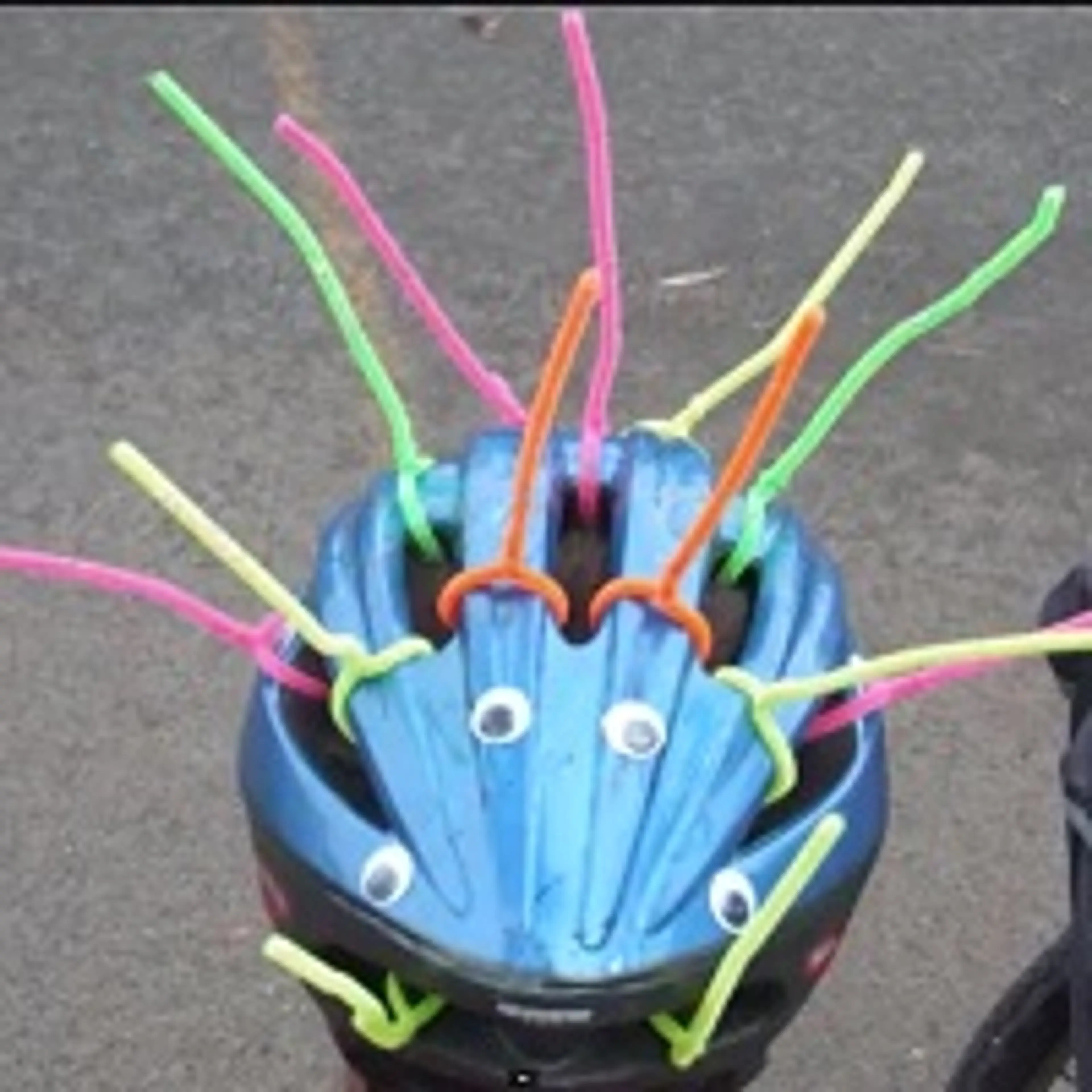 A bike helmet covered in googly eyes and colourful pipe cleaner spikes