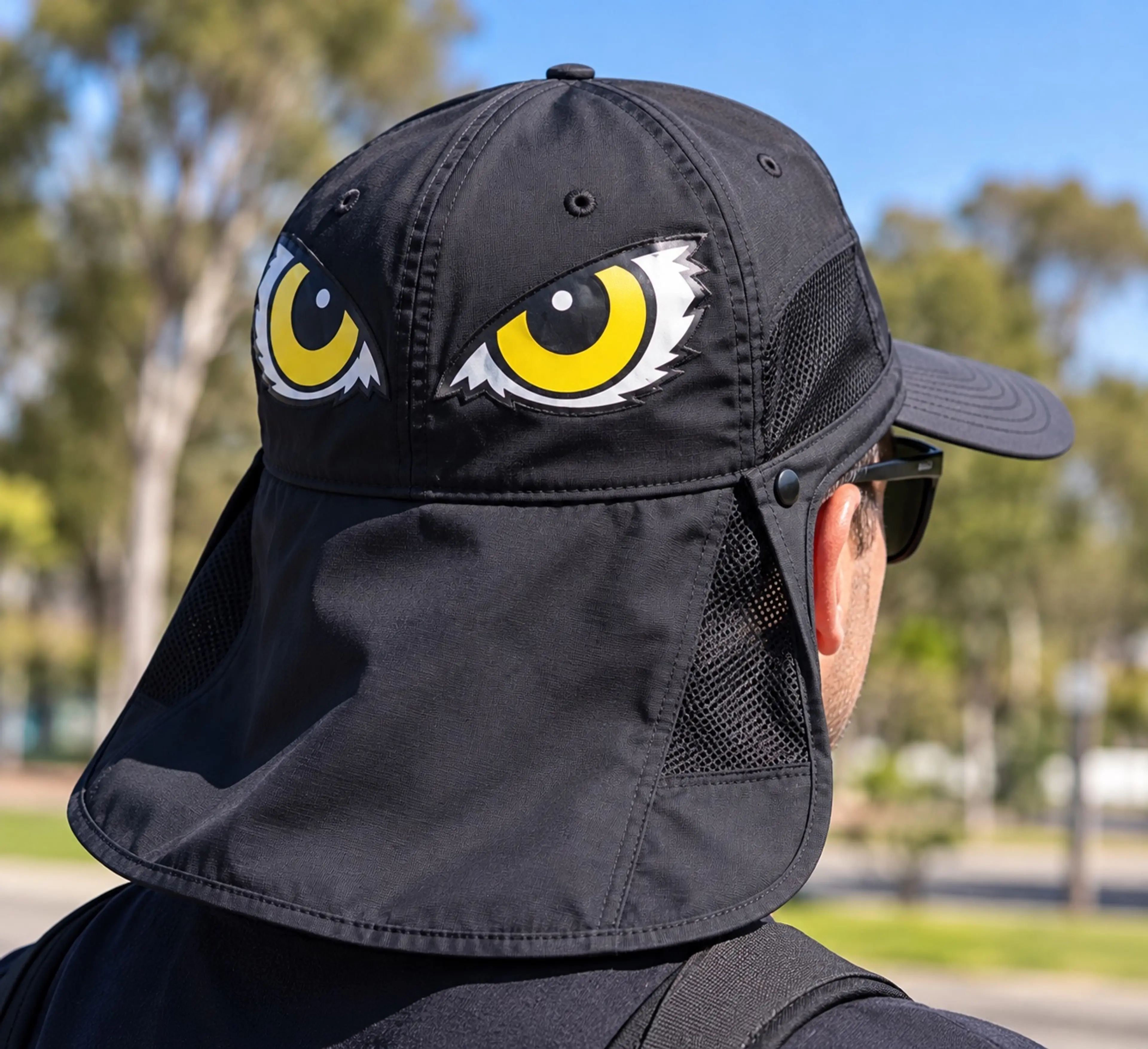 The back of a cap with a neck flap and a pair of large yellow eyes printed on it