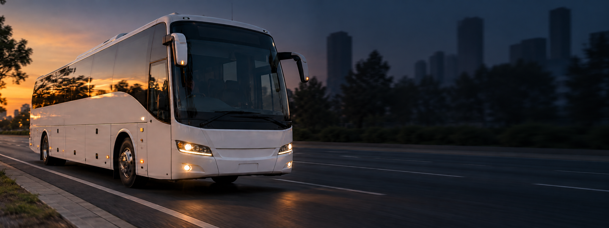 A coach on an arterial road at golden hour, shot from the front three-quarter, city behind it. Dark and cool enough for a panel to sit over the right third. No text in the artwork. 2400x900.