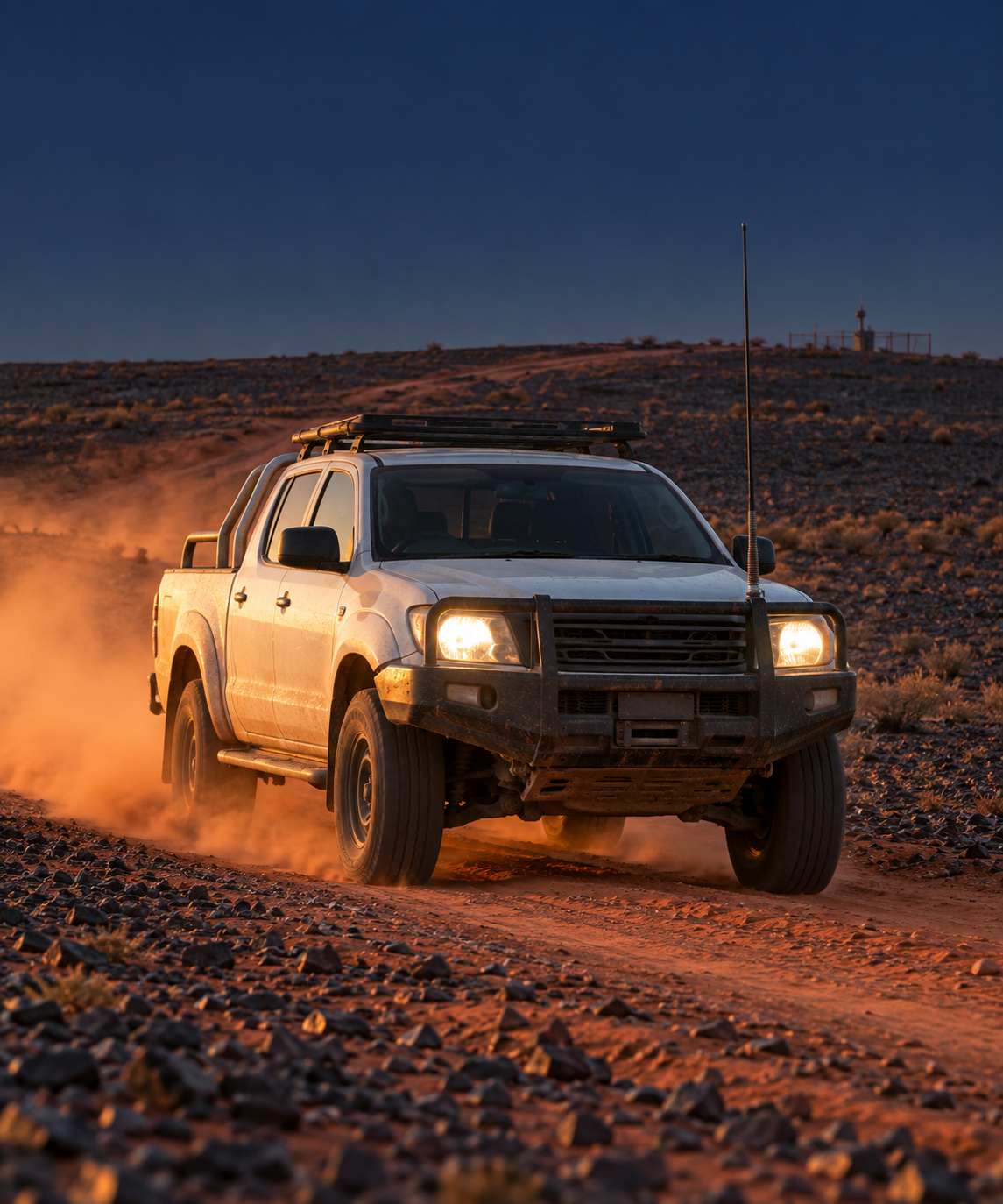 Photograph: a light vehicle on a remote access road at first light. Dark and cool, room at the top, no badges or text in the artwork.