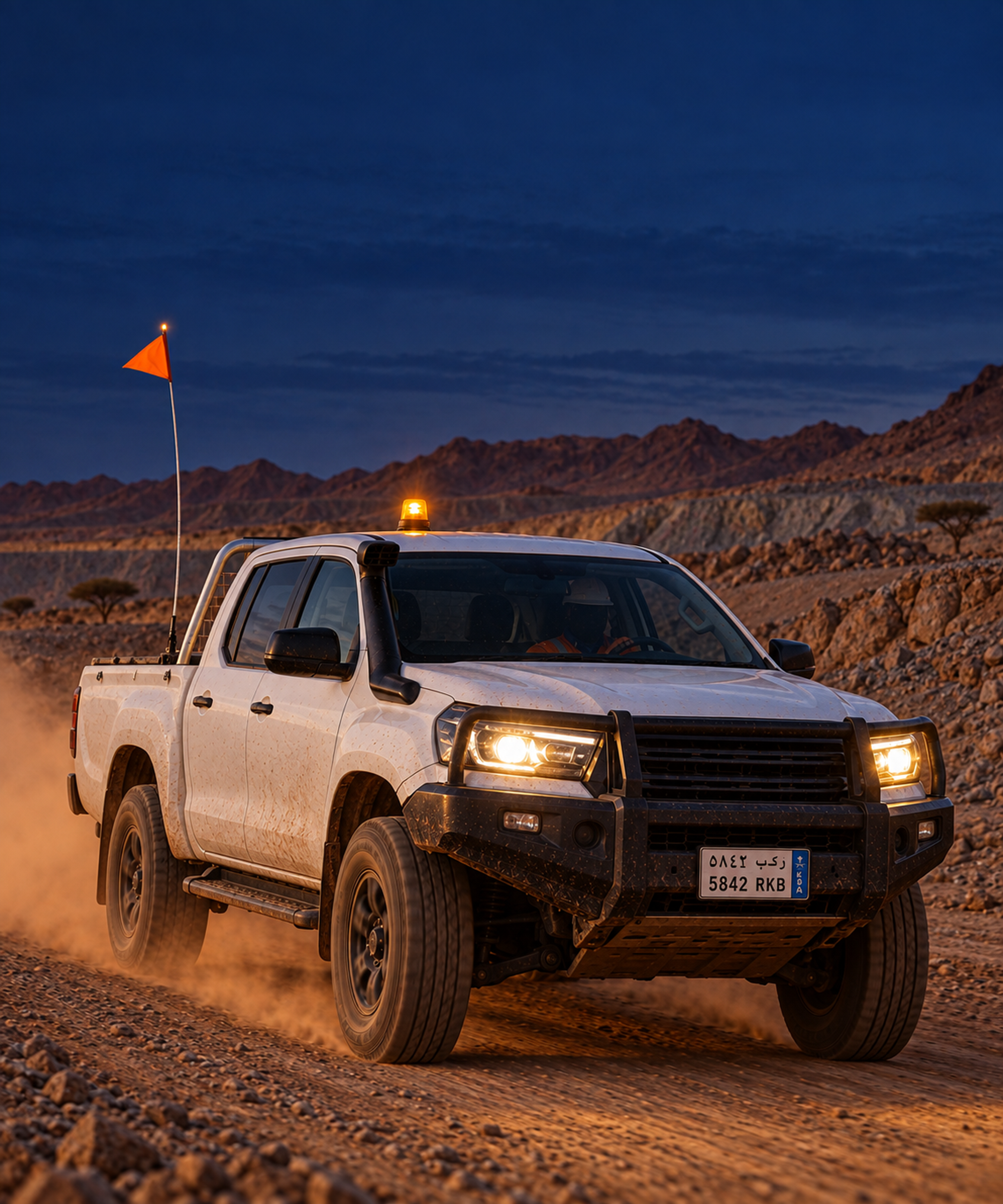 Photograph: a light vehicle on a haul road at first light. Dark and cool, room at the top, no text in the artwork.